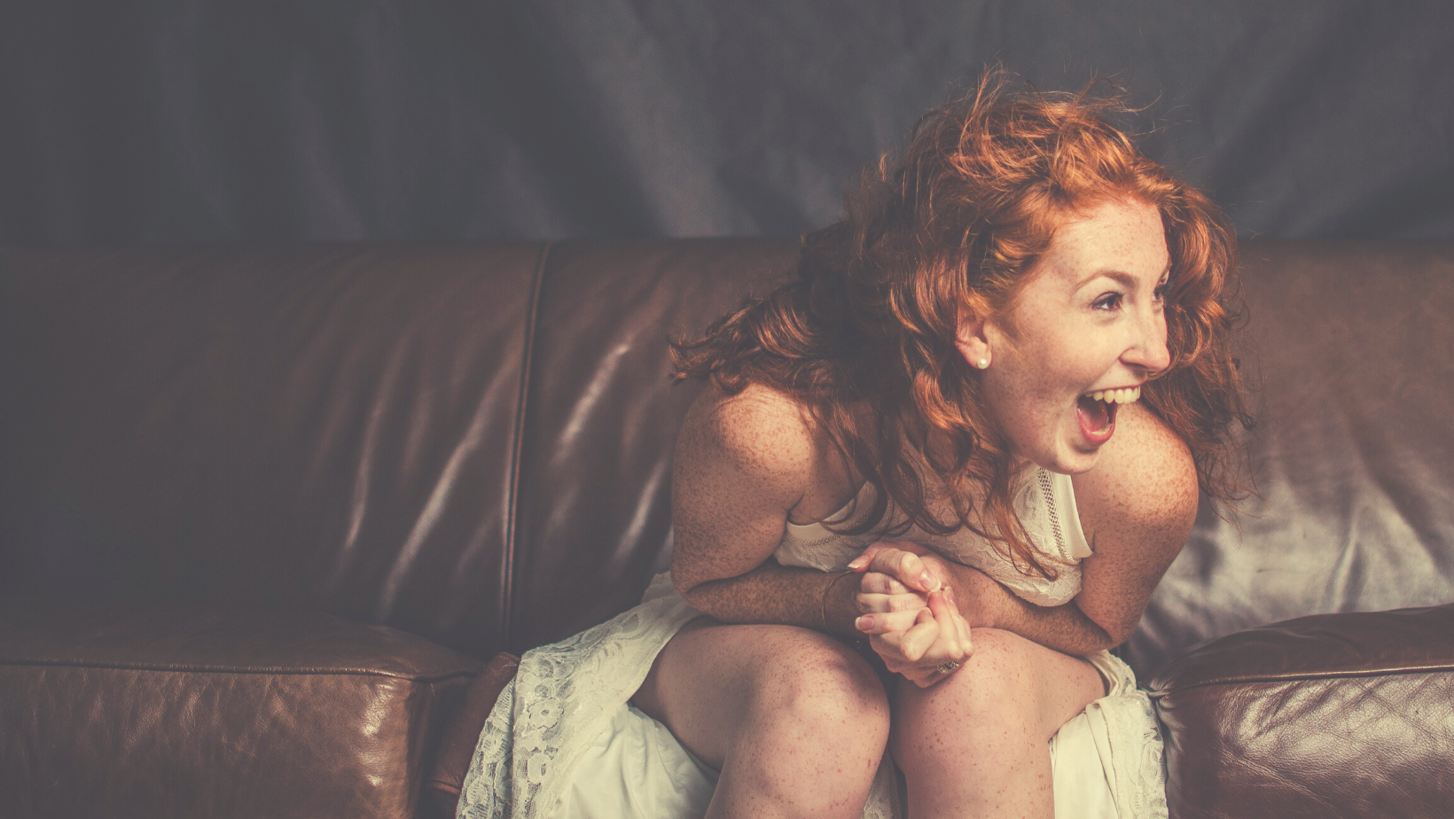 Mujer sentada en un sillón riendo, imagen para Venus en Acuario